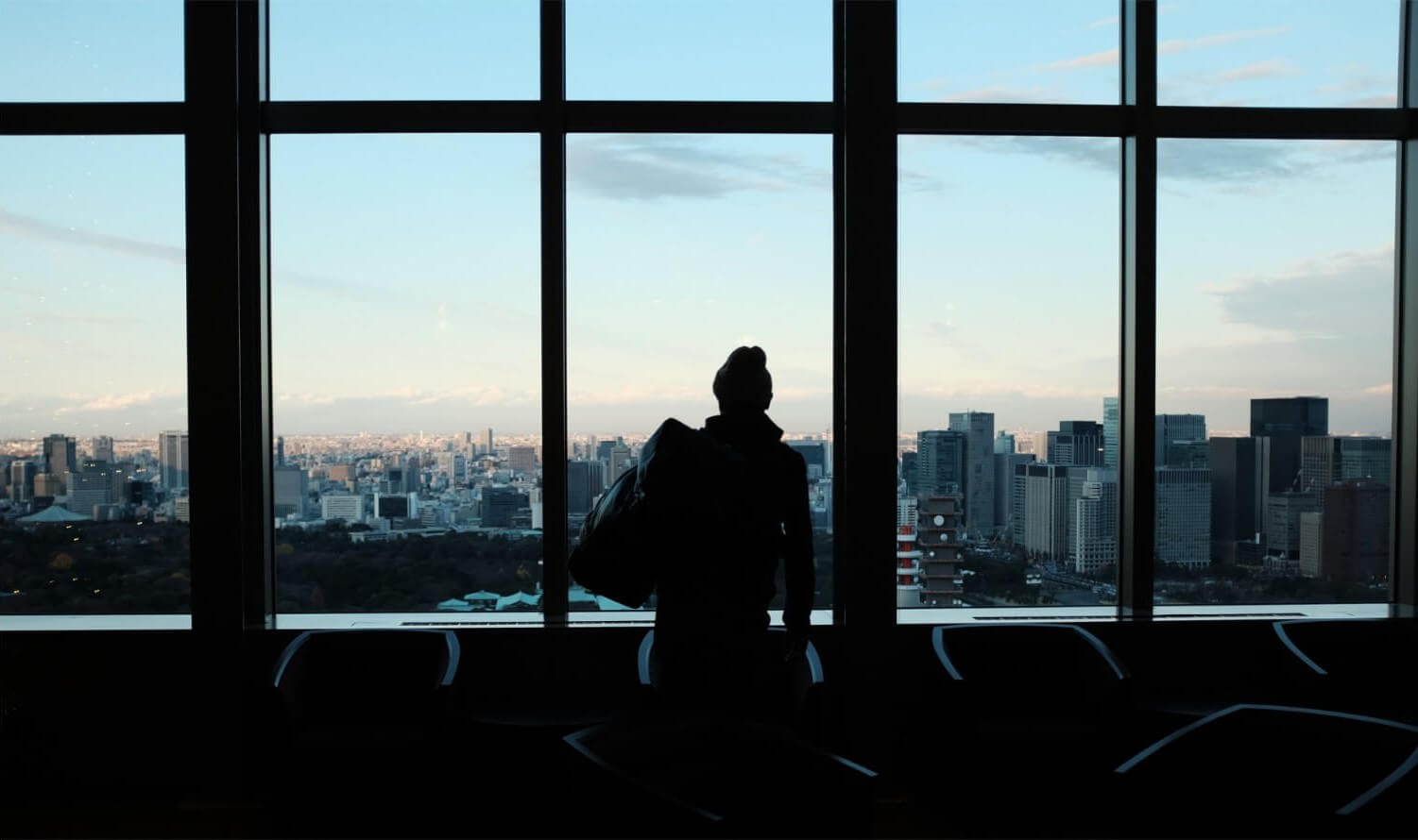Woman staring out a window looking at a city